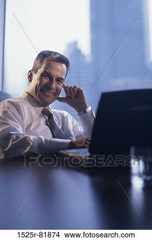 Portrait of a businessman smiling and working on a laptop View Large Photo Image Picture - Portrait of a businessman smiling and working on a laptop. Fotosearch