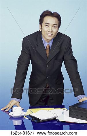 Portrait of a businessman standing behind a desk View Large Photo Image Stock Photo - Portrait of a businessman standing behind a desk. Fotosearch