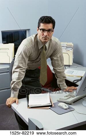 Portrait of a businessman standing behind an office desk View Large Photo Image Stock Photo - Portrait of a businessman standing behind an office desk. Fotosearch