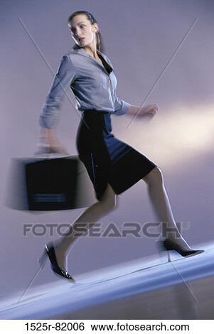 Stock Photograph - Portrait of a businesswoman running holding a briefcase. Fotosearch