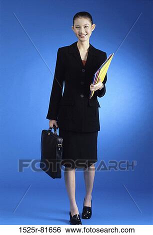 Stock Photograph - Portrait of a businesswoman standing holding a briefcase and files. Fotosearch