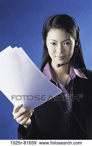 Portrait of a customer service representative wearing a headset holding sheets of paper View Large Photo Image Stock Photo - Portrait of a customer service representative wearing a headset holding sheets of paper. Fotosearch