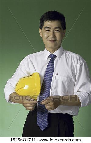 Stock Image - Portrait of a foreman holding a hardhat. Fotosearch