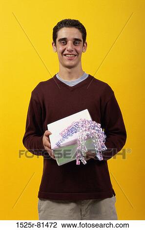 Stock Image - Portrait of a teenager boy holding a gift. Fotosearch