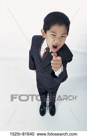 Stock Image - Portrait of a young boy dressed as a businessman pointing. Fotosearch