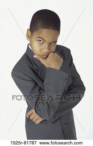 Portrait of a young boy dressed as a businessman standing with his hand on his chin View Large Photo Image Stock Photo - Portrait of a young boy dressed as a businessman standing with his hand on his chin. Fotosearch