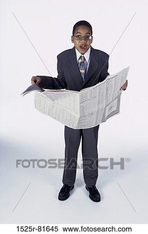 Stock Photography - Portrait of a young boy dressed as a businessman holding a newspaper. Fotosearch