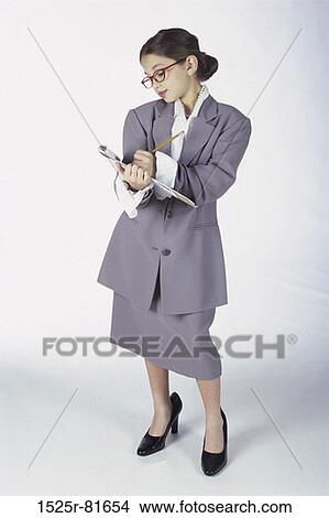 Picture - Portrait of a young girl dressed as a businesswoman writing on a clipboard. Fotosearch
