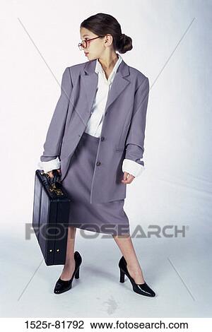 Stock Image - Portrait of a young girl dressed as a businesswoman carrying a briefcase. Fotosearch