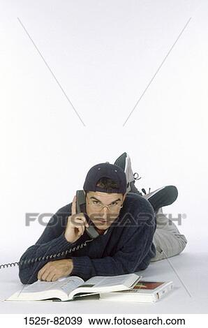 Portrait of a young man lying down talking on a telephone View Large Photo Image Stock Photo - Portrait of a young man lying down talking on a telephone. Fotosearch