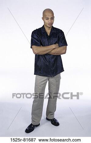 Stock Photo - Portrait of a young man standing with arms folded. Fotosearch