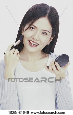 Portrait of a young woman applying make-up View Large Photo Image Stock Photograph - Portrait of a young woman applying make-up. Fotosearch