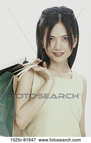Portrait of a young woman carrying a shopping bag View Large Photo Image Stock Photo - Portrait of a young woman carrying a shopping bag. Fotosearch