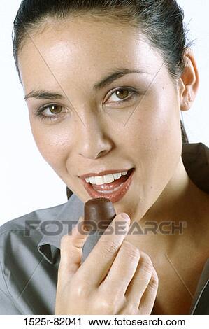 Portrait of a young woman eating a chocolate View Large Photo Image Stock Image - Portrait of a young woman eating a chocolate. Fotosearch