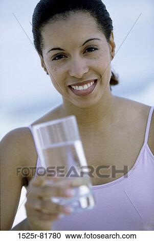 Portrait of a young woman holding a glass of water View Large Photo Image Stock Image - Portrait of a young woman holding a glass of water. Fotosearch