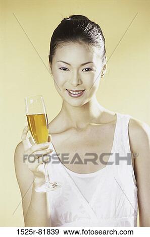 Portrait of a young woman holding a glass of champagne View Large Photo Image Stock Photo - Portrait of a young woman holding a glass of champagne. Fotosearch