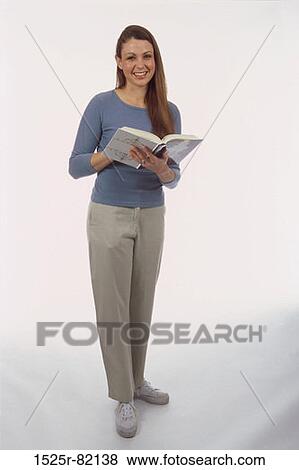 Portrait of a young woman standing with a book View Large Photo Image Stock Photo - Portrait of a young woman standing with a book. Fotosearch