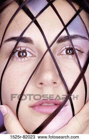 Stock Image - Portrait of a young woman with a crisscross pattern on her face. Fotosearch