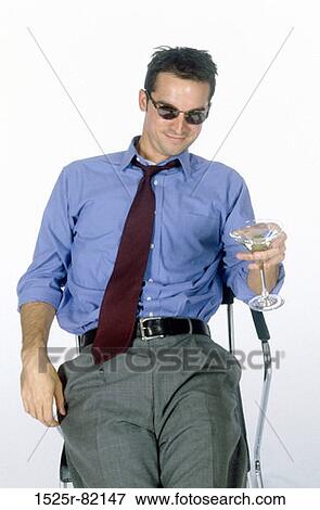 Portrait of young man sitting on a chair holding a glass of wine View Large Photo Image Stock Photo - Portrait of young man sitting on a chair holding a glass of wine. Fotosearch