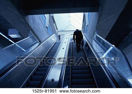 Stock Image - Rear view of a businessman on an escalator. Fotosearch