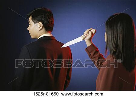Rear view of a businessman with a businesswoman holding a dagger View Large Photo Image Stock Image - Rear view of a businessman with a businesswoman holding a dagger. Fotosearch