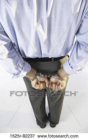 Rear view of a businessman's hands handcuffed behind his back View Large Photo Image Stock Photo - Rear view of a businessman's hands handcuffed behind his back. Fotosearch