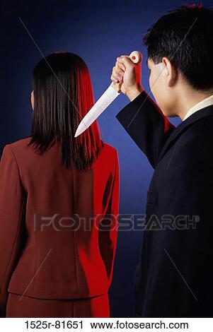 Rear view of a businesswoman with a businessman holding a dagger View Large Photo Image Stock Image - Rear view of a businesswoman with a businessman holding a dagger. Fotosearch