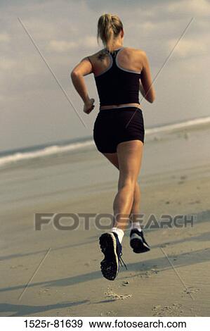Stock Photo - Rear view of a young woman running on the beach. Fotosearch