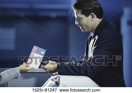 Stock Photo - Side profile of a businessman standing at an airport counter. Fotosearch