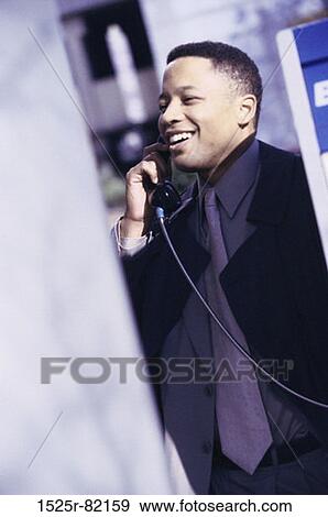Stock Photo - Side profile of a businessman talking on a pay phone. Fotosearch