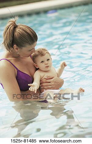 Stock Photography - Side profile of a mother playing with her baby boy in a swimming pool. Fotosearch