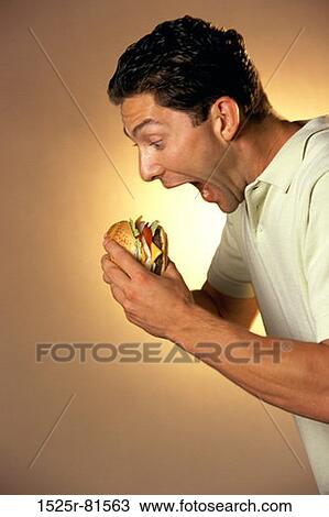 Side profile of a young man eating a burger View Large Photo Image Stock Image - Side profile of a young man eating a burger. Fotosearch