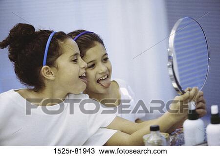 Side profile of two girls looking in a mirror making faces View Large Photo Image Stock Image - Side profile of two girls looking in a mirror making faces. Fotosearch