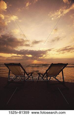 Stock Photo - Silhouette of two deck chairs at the beach during sunset. Fotosearch