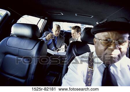 Two businessmen talking to each other in a car View Large Photo Image Stock Image - Two businessmen talking to each other in a car. Fotosearch