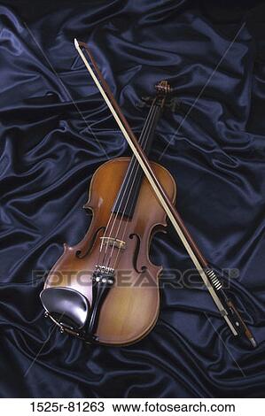 Stock Image - Violin and a bow on blue fabric. Fotosearch