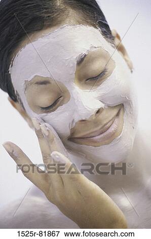 Woman applying a face mask smiling View Large Photo Image Stock Photo - Woman applying a face mask smiling. Fotosearch