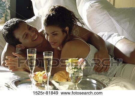 Young couple lying on a bed together View Large Photo Image Stock Photo - Young couple lying on a bed together. Fotosearch