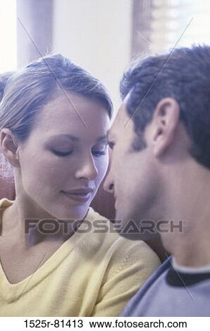 Stock Image - Young couple sitting face to face on a couch. Fotosearch