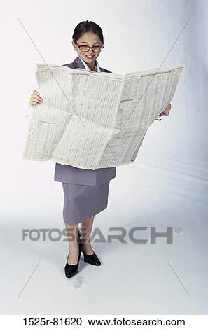 Stock Image - Young girl dressed as a businesswoman holding a newspaper. Fotosearch