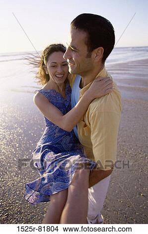 Young man carrying a young woman on the beach View Large Photo Image Picture - Young man carrying a young woman on the beach. Fotosearch