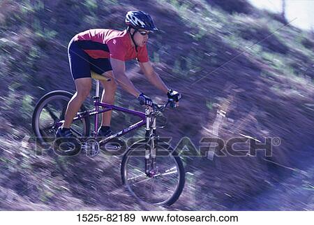 Young man cycling down a hill View Large Photo Image Stock Photo - Young man cycling down a hill. Fotosearch