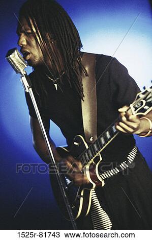 Stock Image - Young man playing a guitar and singing. Fotosearch