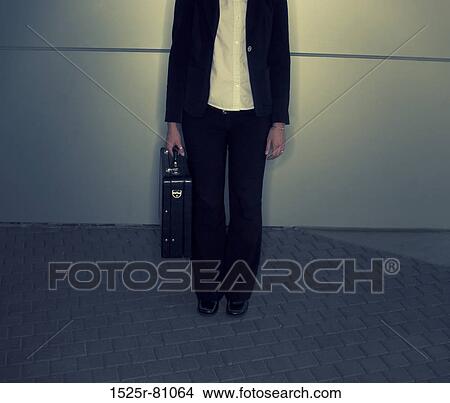 Body shot of woman dressed in black and white clothing standing in front of gray background View Large Photo Image Picture - Body shot of woman dressed in black and white clothing standing in front of gray background. Fotosearch