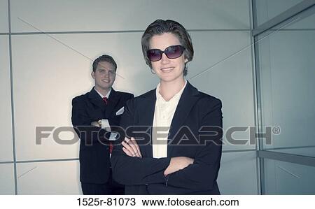 Stock Image - Business man and business woman pose as they stand next to each other. Fotosearch