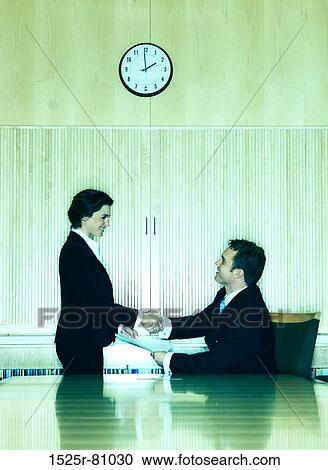 Business man and business woman shake hands at the end of the conference table View Large Photo Image Stock Image - Business man and business woman shake hands at the end of the conference table. Fotosearch