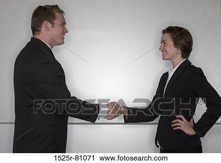 Stock Image - Business man and business woman shaking hands. Fotosearch