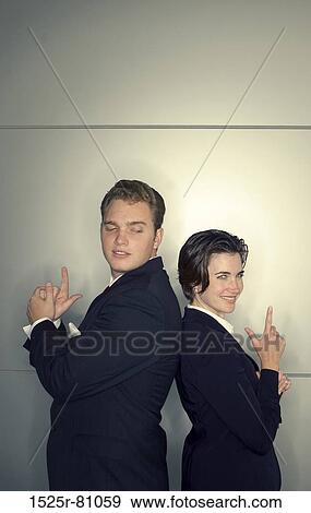 Stock Photo - Business man and business woman stand back to back with their hands shaped like guns. Fotosearch
