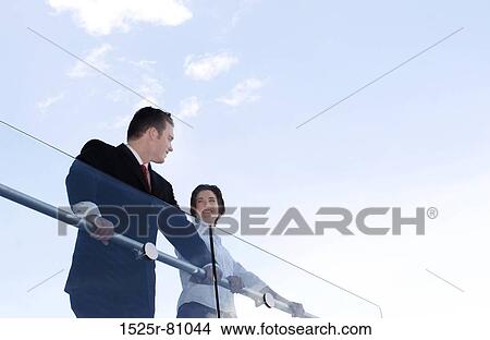 Business man and woman smile as they stand over the rail View Large Photo Image Picture - Business man and woman smile as they stand over the rail. Fotosearch