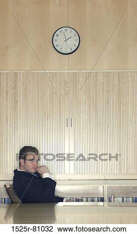 Business man in black suit and blue tie sits underneath clock at the head of the conference table View Large Photo Image Stock Image - Business man in black suit and blue tie sits underneath clock at the head of the conference table. Fotosearch